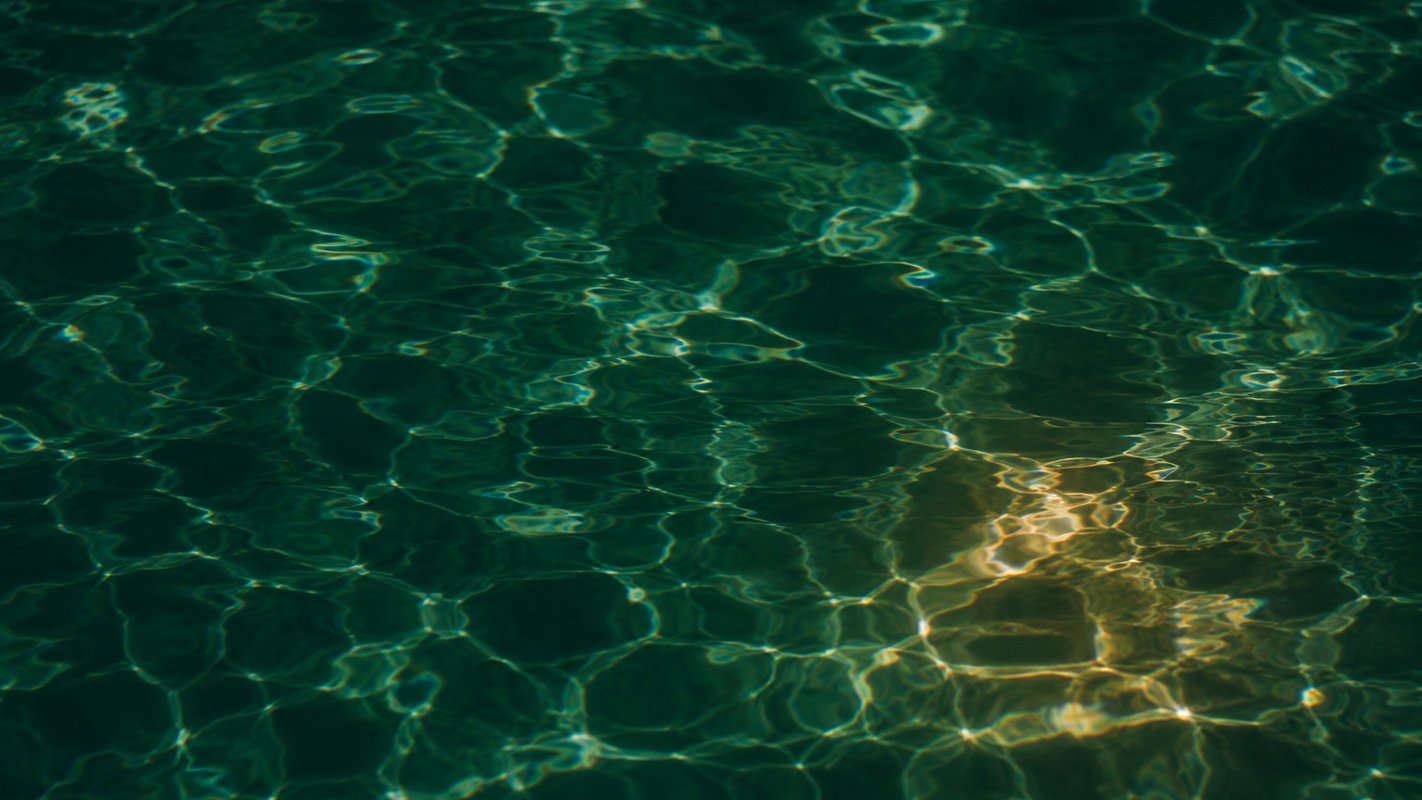 uperficie d'acqua verde attraversata dalla luce, immagine della trasparenza e della lettura oltre la superficie.